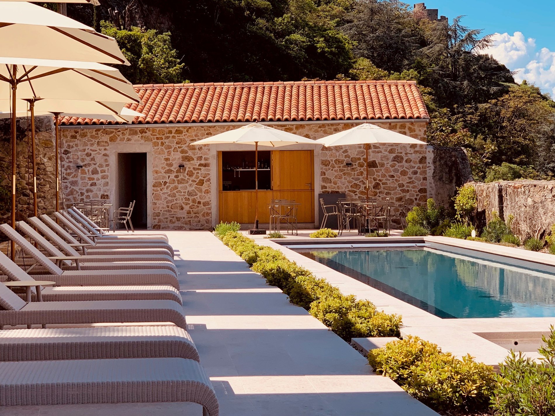 Hotel pool with stone building and lounge chairs