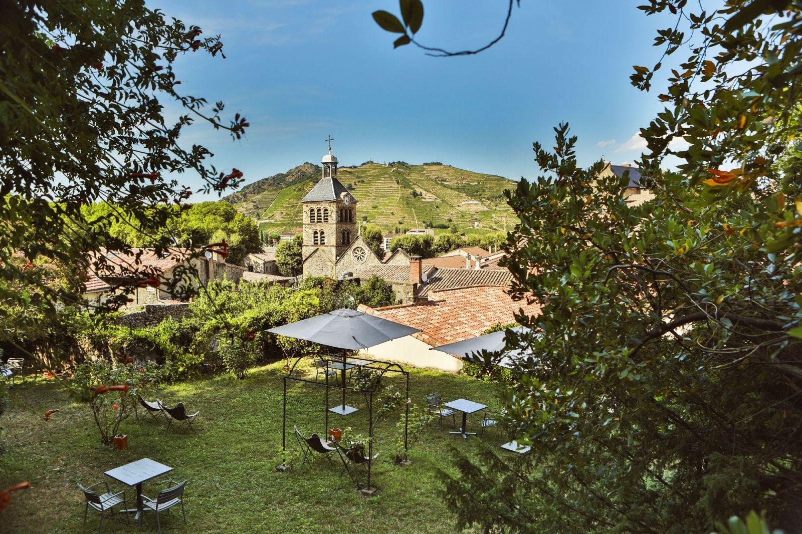 Hotel garden with umbrellas overlooking church and Hermitage vineyards