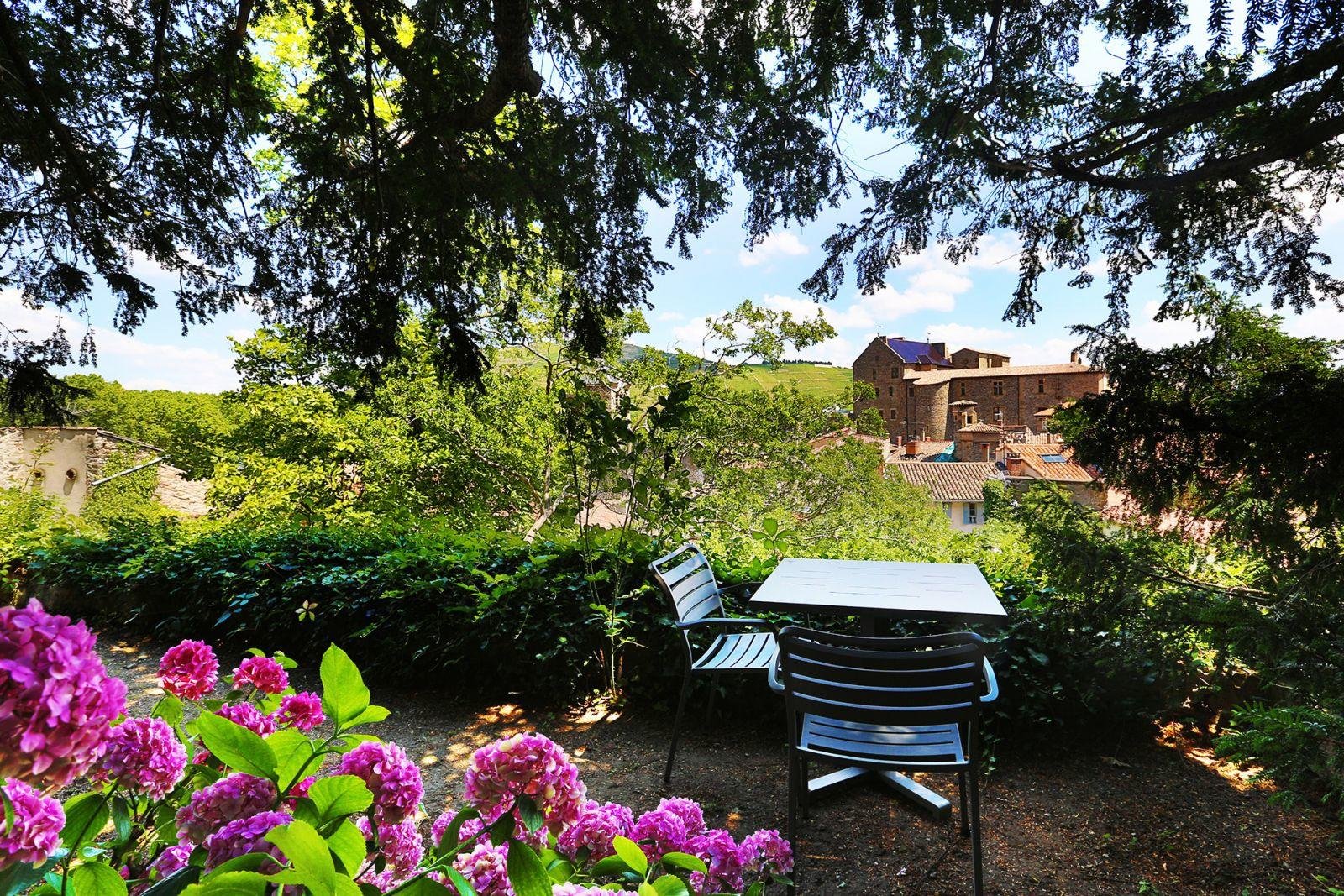 Hotel garden seating area with pink flowers and vineyard views