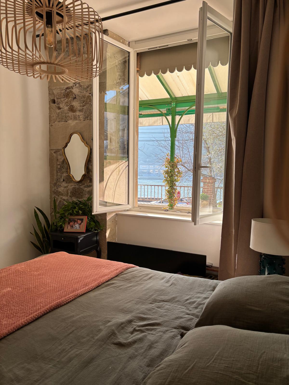 Bedroom with open window overlooking terrace and Rhône River