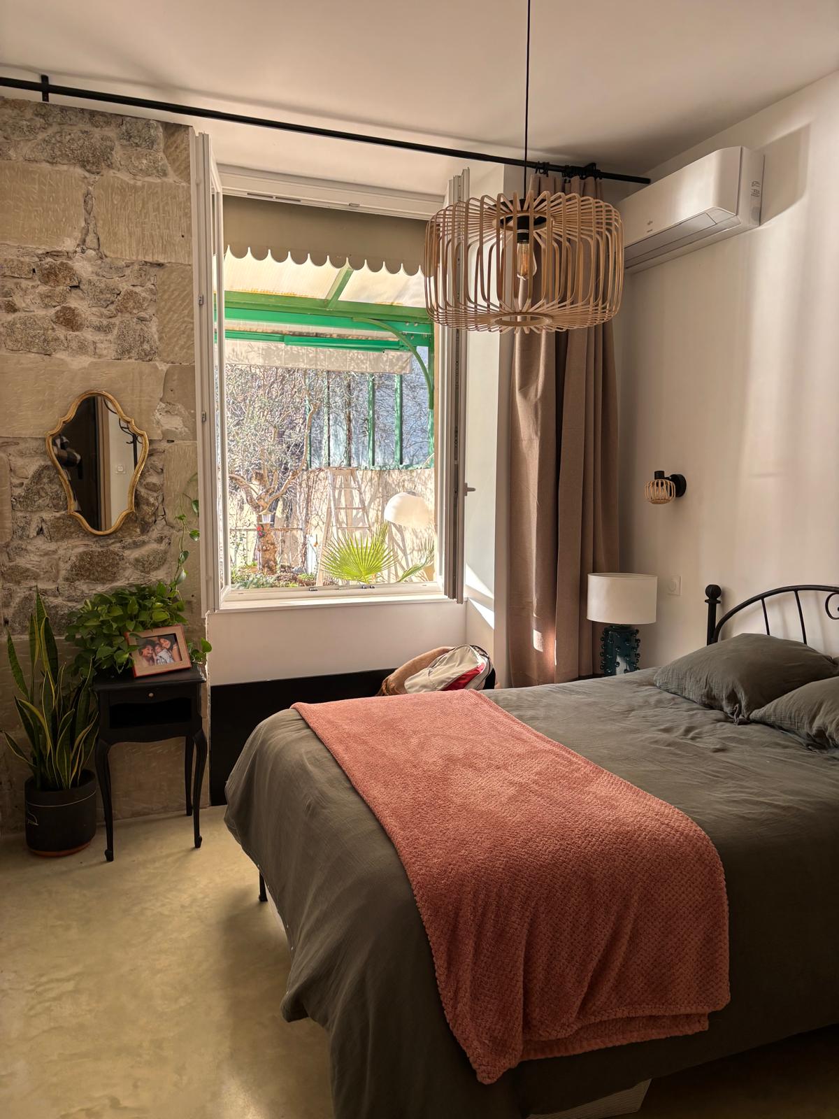 Cozy bedroom with exposed stone wall and terrace view